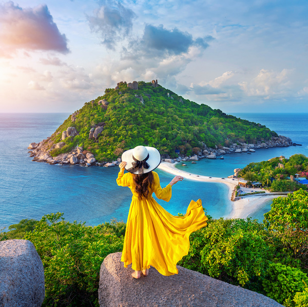 Photographie d'une femme en jaune devant une île
