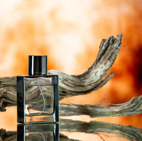 Photographie d'un flacon de parfum devant une branche